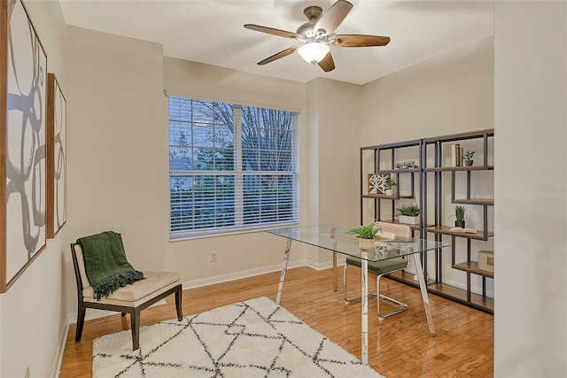 home office with a ceiling fan, baseboards, and wood finished floors