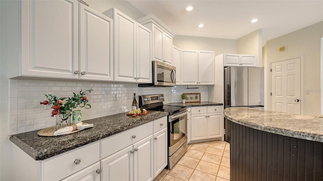 kitchen featuring stainless steel appliances, white cabinetry, dark stone countertops, and light tile patterned floors