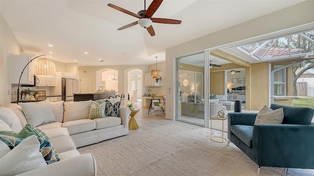 living area featuring arched walkways, ceiling fan, light tile patterned floors, and recessed lighting