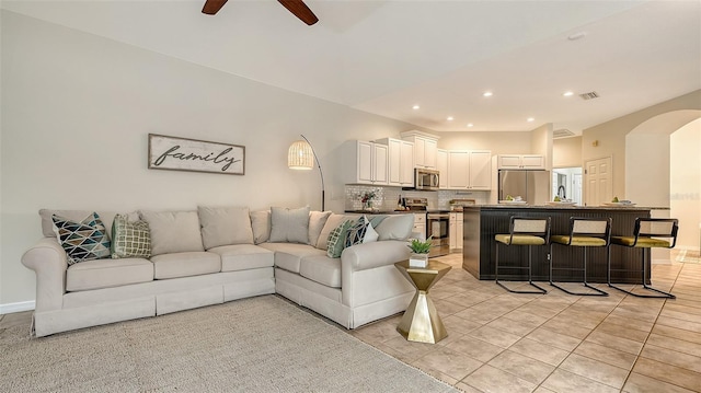 living room with light tile patterned floors, visible vents, arched walkways, ceiling fan, and recessed lighting