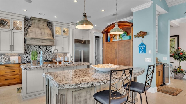 kitchen featuring stainless steel built in fridge, custom exhaust hood, white cabinets, and a kitchen island with sink