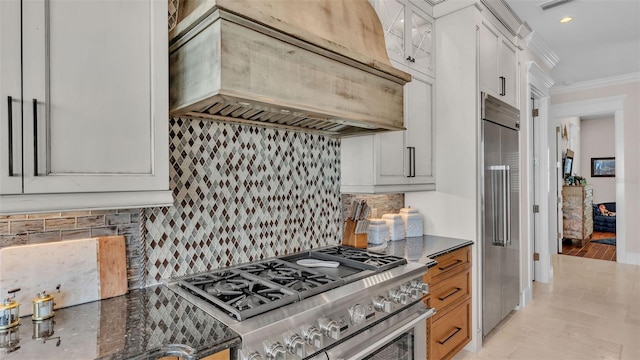 kitchen with white cabinetry, ornamental molding, backsplash, premium range hood, and premium appliances