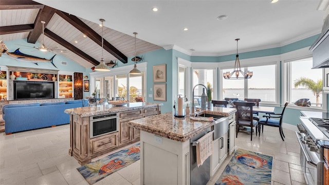 kitchen featuring light stone counters, lofted ceiling with beams, decorative light fixtures, stainless steel appliances, and a kitchen island with sink