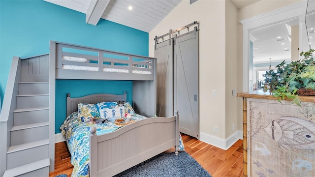 bedroom featuring wooden ceiling, lofted ceiling with beams, hardwood / wood-style flooring, and a barn door