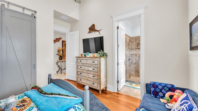 bedroom featuring ensuite bathroom, wood-type flooring, and a barn door