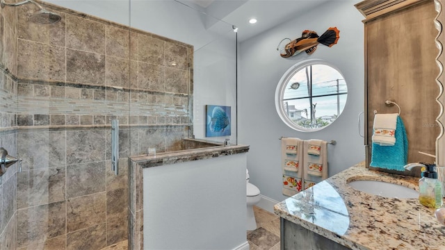 bathroom featuring a tile shower, vanity, and toilet