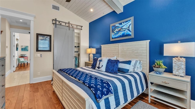 bedroom with hardwood / wood-style flooring, a barn door, lofted ceiling with beams, and wood ceiling