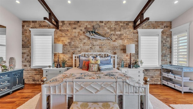 bedroom featuring light hardwood / wood-style floors and beam ceiling