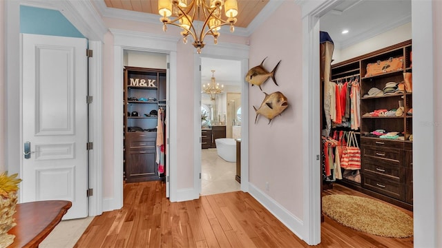 hallway with a notable chandelier, crown molding, and wood-type flooring