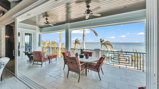 sunroom featuring plenty of natural light, ceiling fan, wood ceiling, and a water view