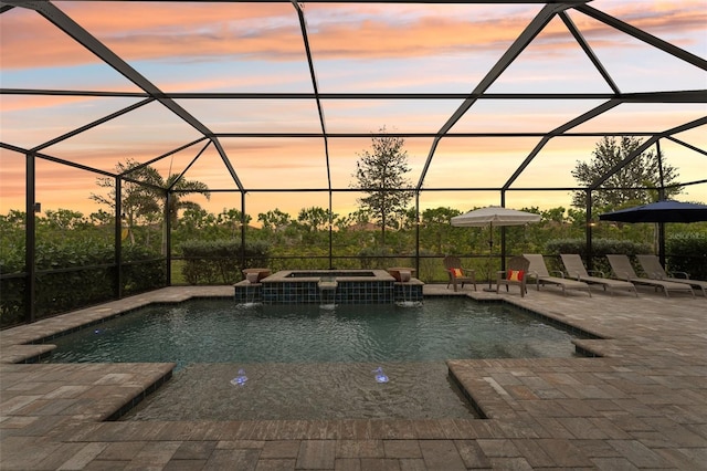 pool at dusk featuring a patio area, a lanai, and an in ground hot tub