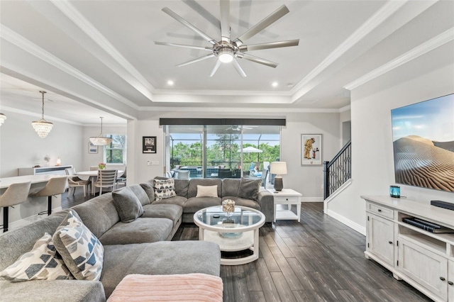 living room featuring dark hardwood / wood-style floors, ceiling fan, a raised ceiling, and crown molding