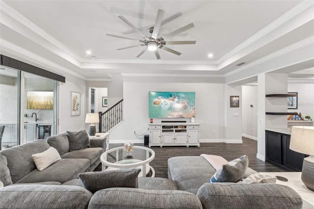 living room featuring a tray ceiling, ceiling fan, dark hardwood / wood-style flooring, and ornamental molding