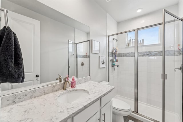 bathroom featuring vanity, toilet, and a shower with door