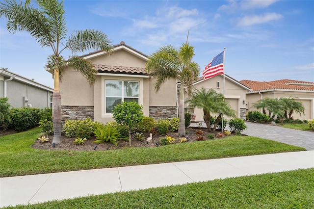 mediterranean / spanish home with an attached garage, stone siding, a tile roof, stucco siding, and decorative driveway