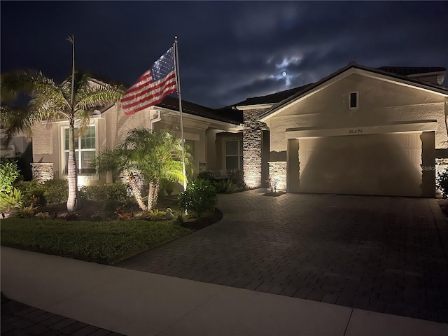 20296 Bandera Pl, Venice, FL 34293 - view of front of house featuring decorative driveway, a garage, stucco siding, and stone siding