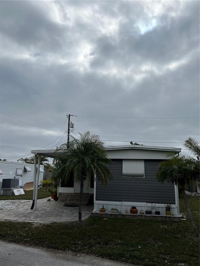 manufactured / mobile home with a patio, central air condition unit, and a front lawn