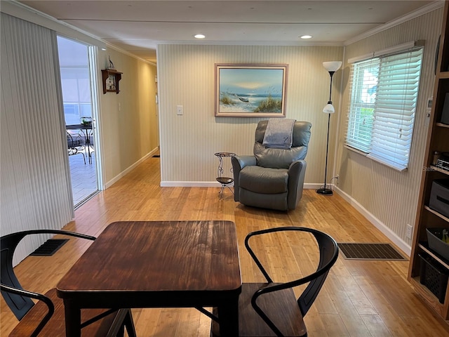 living area featuring crown molding and light hardwood / wood-style flooring