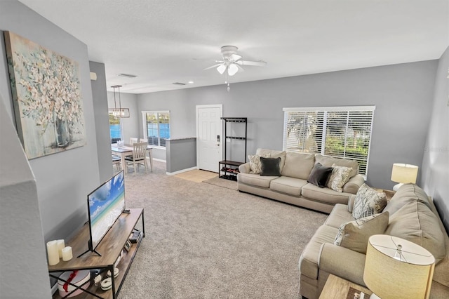 living room featuring light carpet and ceiling fan with notable chandelier