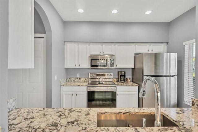 kitchen with white cabinetry, light stone countertops, and appliances with stainless steel finishes