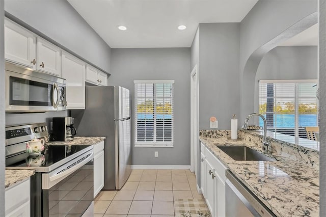 kitchen featuring light stone counters, stainless steel appliances, sink, white cabinets, and light tile patterned flooring