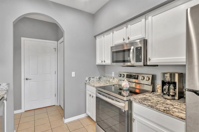 kitchen featuring light tile patterned flooring, light stone counters, white cabinetry, and stainless steel appliances