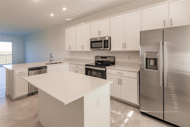 kitchen featuring appliances with stainless steel finishes, kitchen peninsula, a kitchen island, sink, and white cabinetry