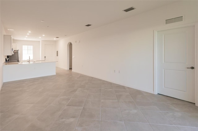 unfurnished living room with sink and light tile patterned floors