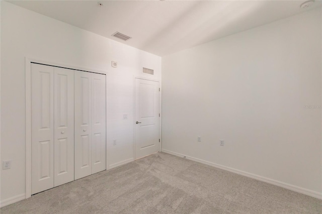 unfurnished bedroom with a closet and light colored carpet