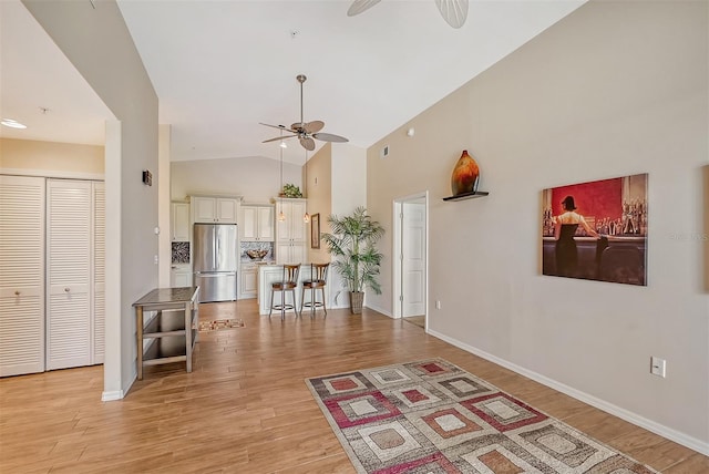 living room featuring ceiling fan, light hardwood / wood-style flooring, and vaulted ceiling