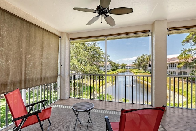 sunroom featuring a water view and ceiling fan