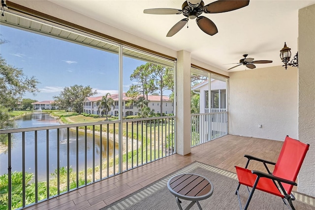 sunroom featuring ceiling fan, a healthy amount of sunlight, and a water view