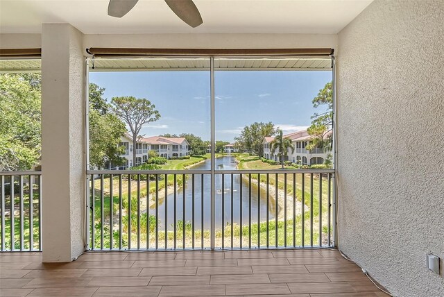 sunroom featuring ceiling fan and a water view