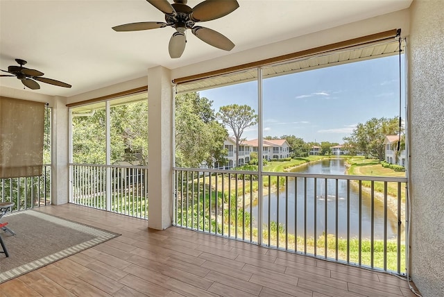 unfurnished sunroom with ceiling fan, a healthy amount of sunlight, and a water view