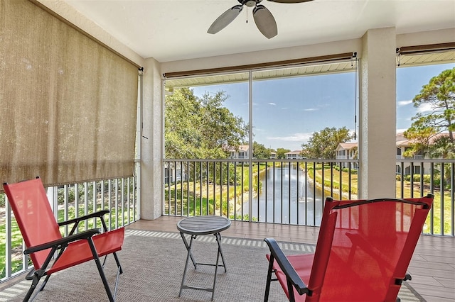 sunroom / solarium featuring a water view and ceiling fan