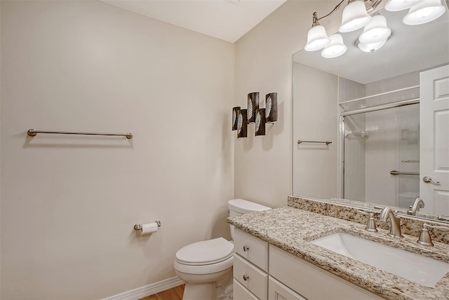 bathroom with a shower with door, vanity, and toilet