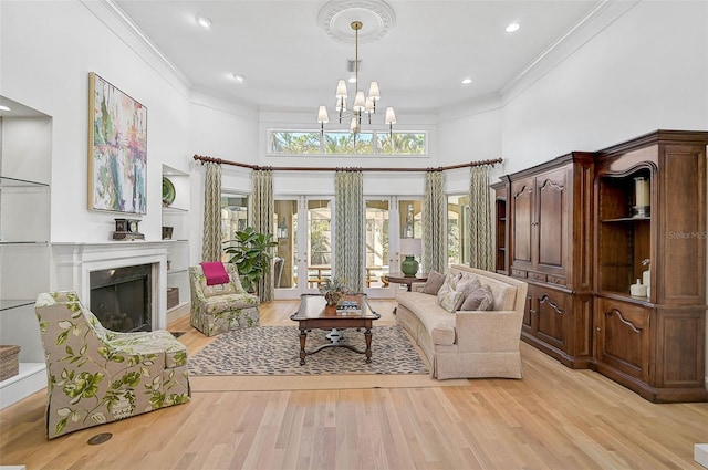 living area featuring ornamental molding, light hardwood / wood-style floors, a chandelier, and a high ceiling