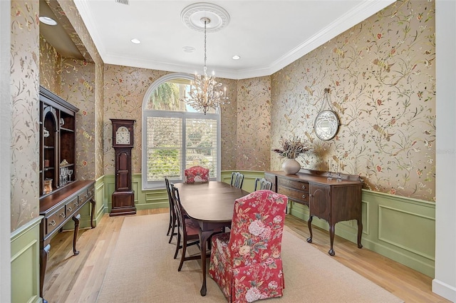 dining space with ornamental molding, a chandelier, and light wood-type flooring