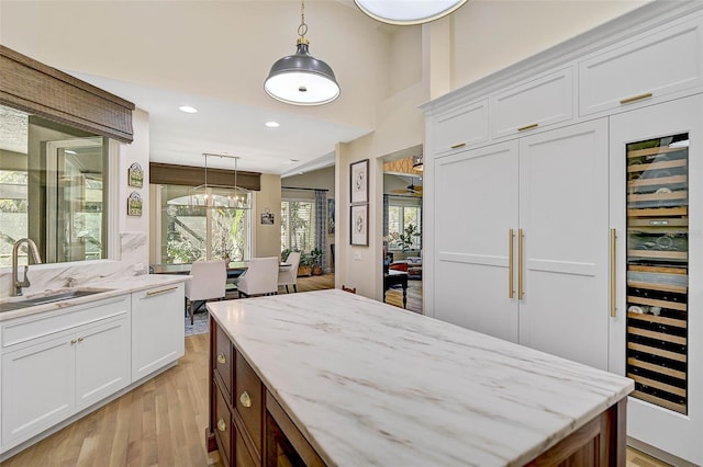 kitchen with white cabinetry, sink, and decorative light fixtures