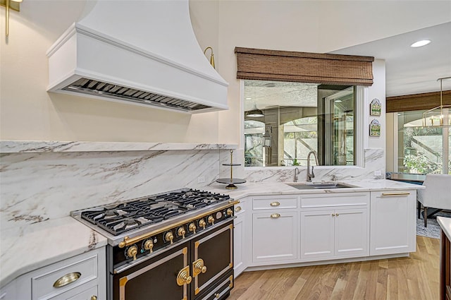 kitchen featuring sink, premium range hood, white cabinetry, double oven range, and light stone counters