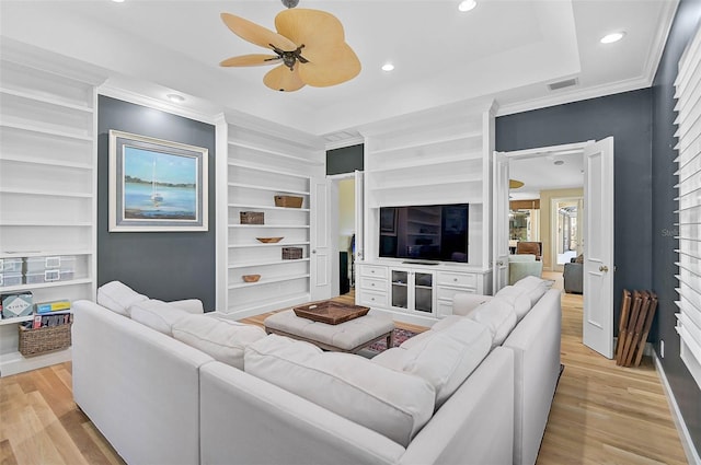 living room with crown molding, a tray ceiling, light hardwood / wood-style floors, and ceiling fan