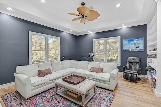 living room featuring crown molding, ceiling fan, a raised ceiling, and light hardwood / wood-style flooring