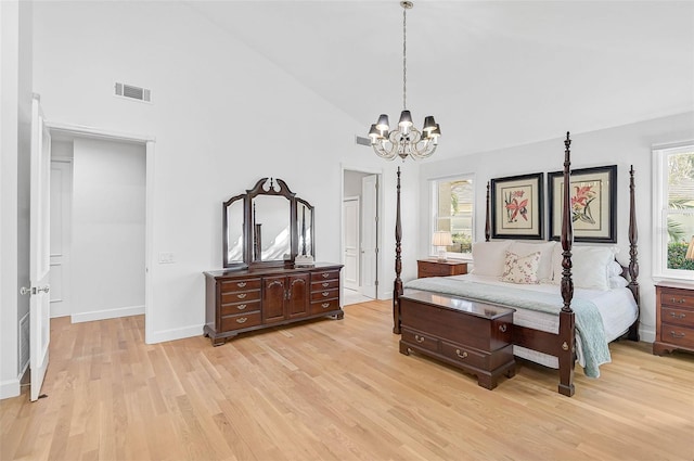 bedroom with an inviting chandelier, high vaulted ceiling, and light hardwood / wood-style floors