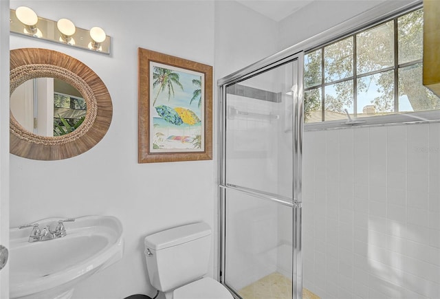 bathroom with toilet, sink, and a shower with shower door