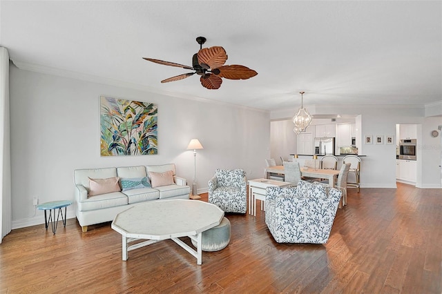 living room featuring hardwood / wood-style flooring, ornamental molding, and ceiling fan with notable chandelier