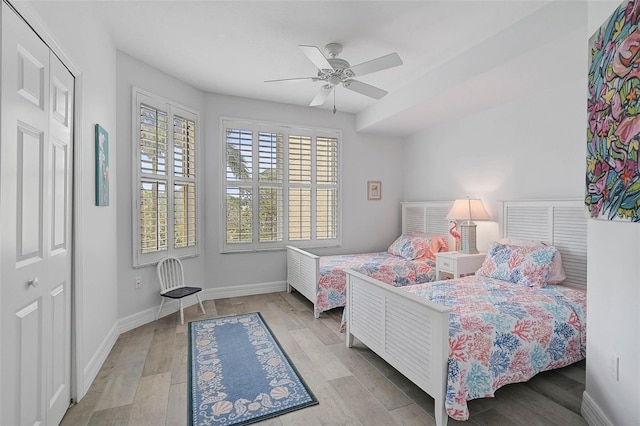 bedroom with light hardwood / wood-style floors, ceiling fan, and a closet