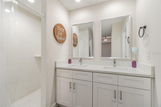 bathroom with a tile shower and vanity