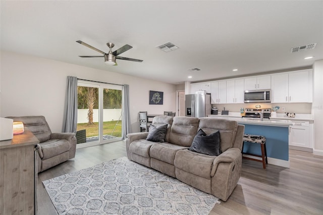 living room with ceiling fan, sink, and light hardwood / wood-style floors