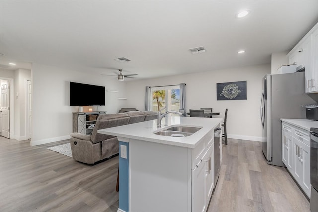 kitchen featuring light wood-type flooring, a kitchen island with sink, sink, and white cabinetry