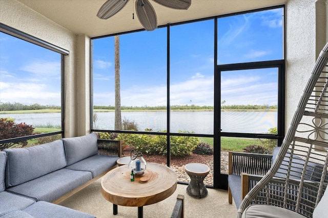 sunroom featuring ceiling fan and a water view